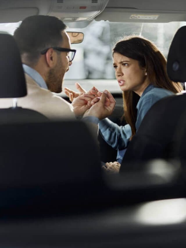 Young displeased couple having communication problems inside of a car.
