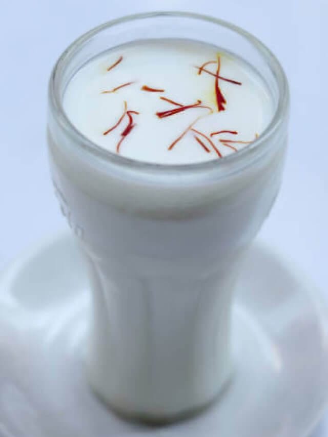 Full glass of milk with saffron in it against white background.