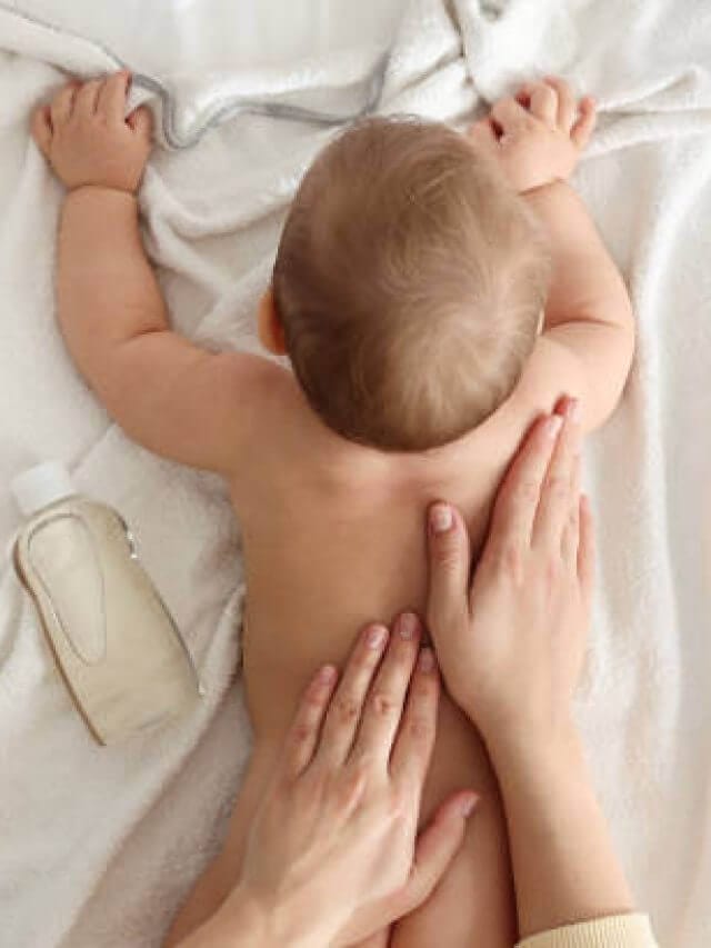 Mother massaging her baby with oil on towel after bathing, top view