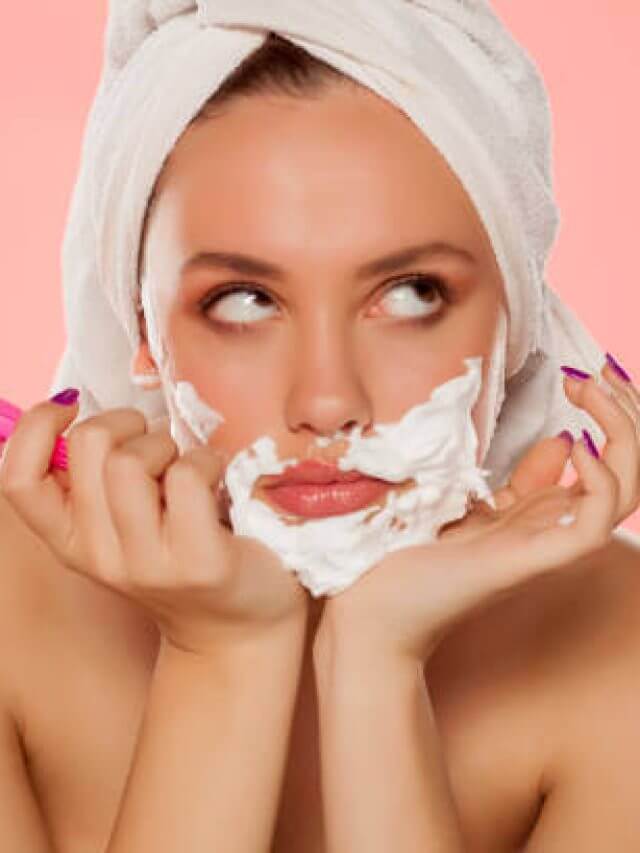 disappointed young woman with foam on the face and a razor in her hand