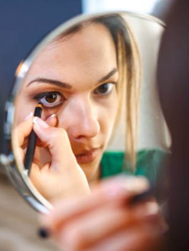 Beautiful woman applying kajal eyeliner on her eyes