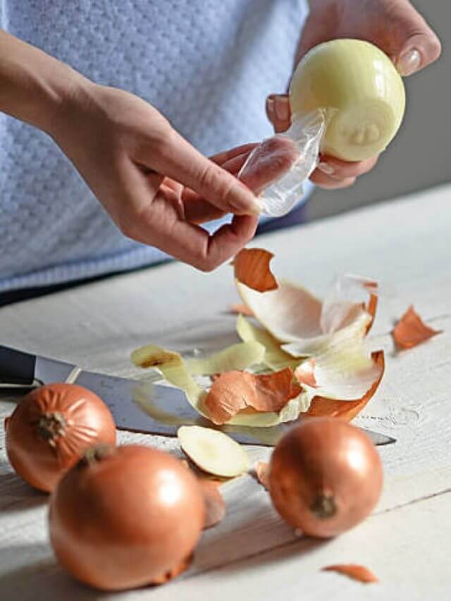 Woman hand peel fresh onion on white table
