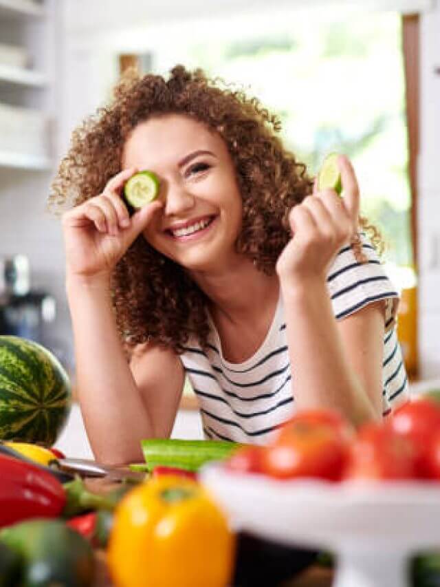 Woman holding a slice of cucumber