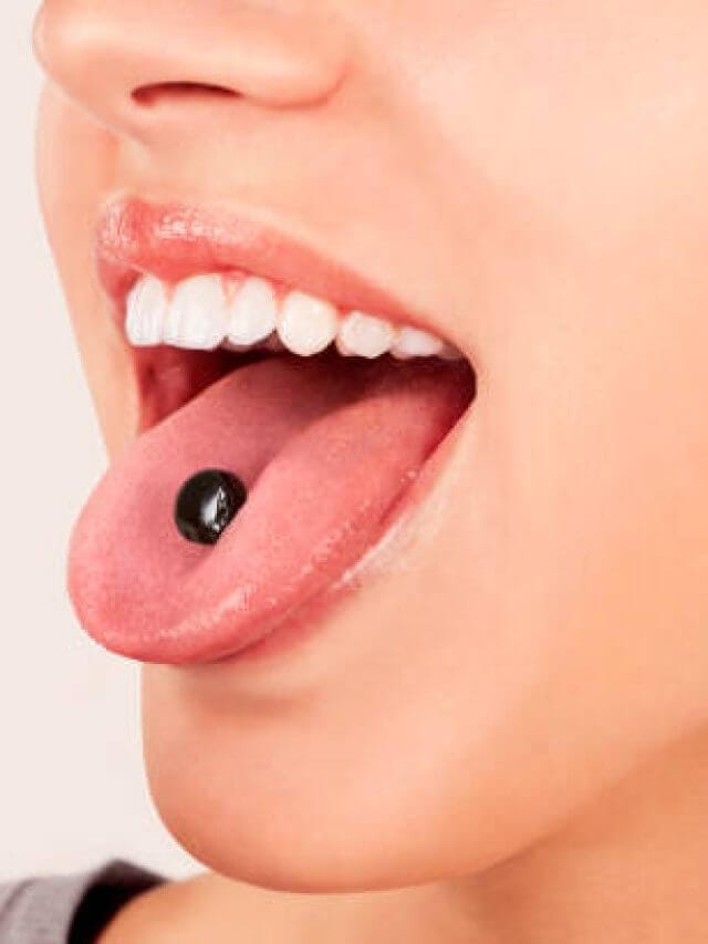 Sexy girl with shilajit pill on tongue close up. Taking dietary supplements.