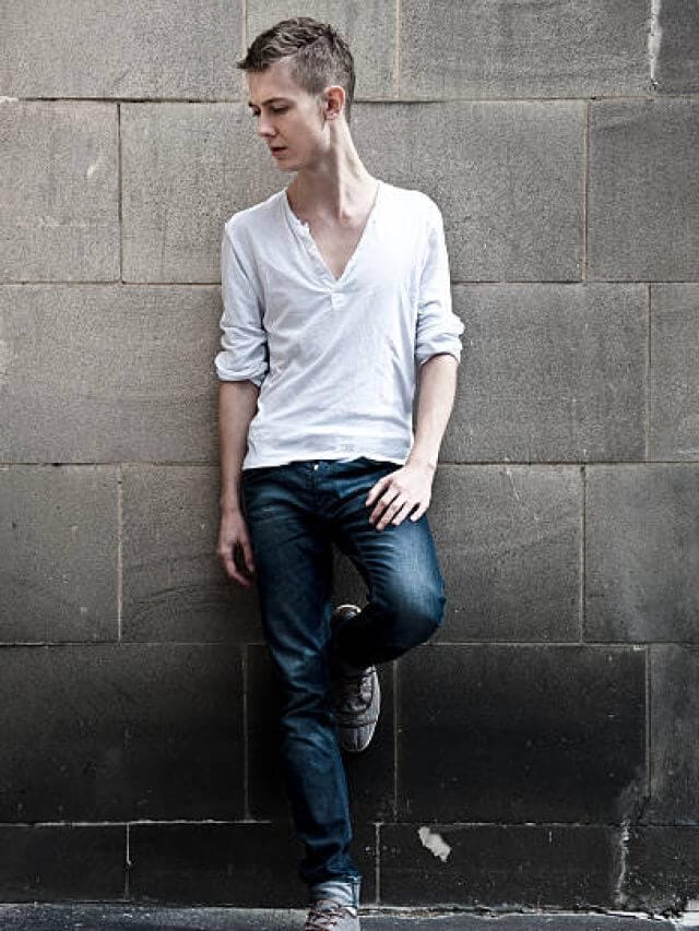 portrait of young man standing against a dirty wall