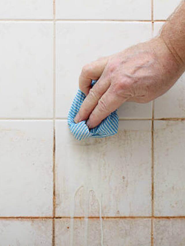 cleaning dirty shower and bathroom tiles with mould with blue cloth