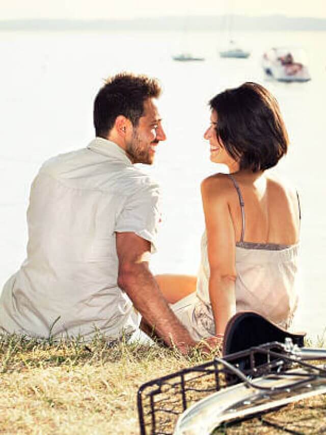Couple with bicycle flirting in front of the lake