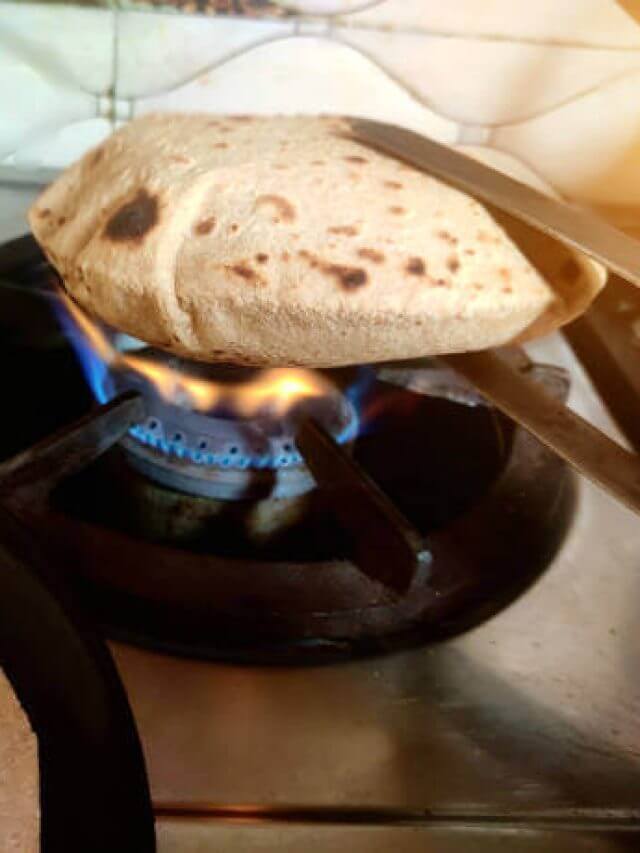 Roti , chapati or bread making on gas stove in indian home kitchen
