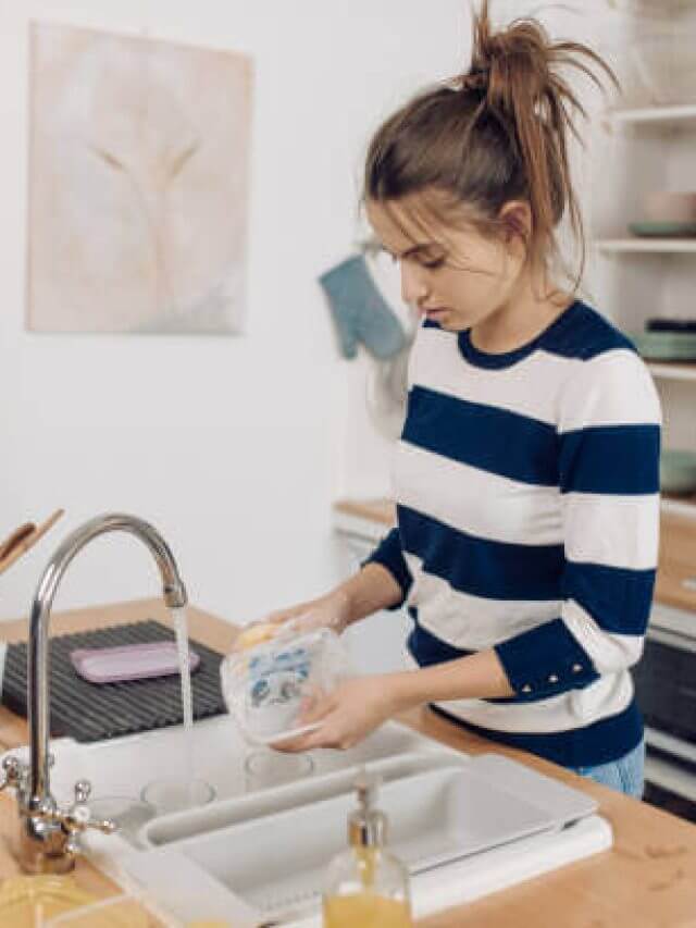 Portrait of a girl washing a plastic food box at her kitchen.