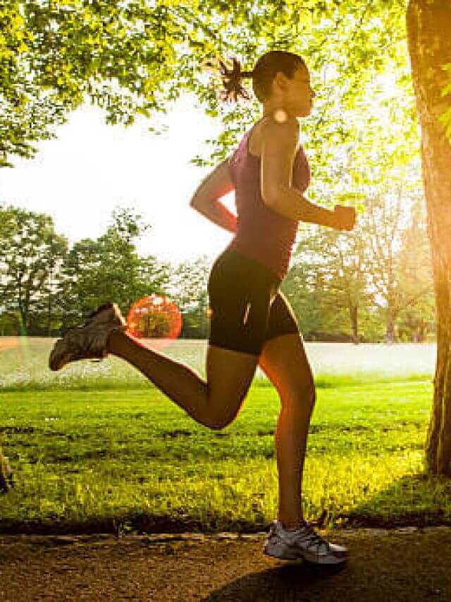 Young woman jogging in park at sunset.